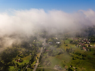 Fototapeta na wymiar Thin morning fog over a mountain village. Fog covers the Ukrainian slopes of the mountains. Aerial drone view.