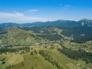 Green mountains of the Ukrainian Carpathians on a sunny summer morning. Coniferous trees on the mountain slopes and green grass. Aerial drone view.