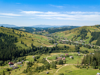 Fototapeta na wymiar Green mountains of the Ukrainian Carpathians on a sunny summer morning. Coniferous trees on the mountain slopes and green grass. Aerial drone view.