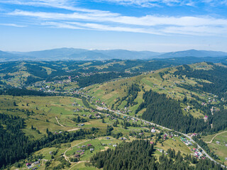 Fototapeta premium Green mountains of the Ukrainian Carpathians on a sunny summer morning. Coniferous trees on the mountain slopes and green grass. Aerial drone view.