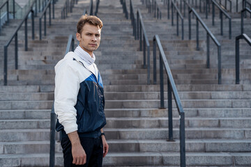 Sportsman standing against steps, looking at camera