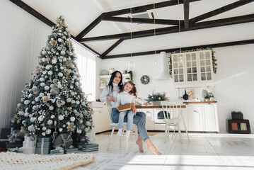 Obraz premium Mom with a little girl unpack gifts. Holiday.