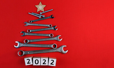 Christmas tree made of tools on a red background with wooden cubes "2022 year"