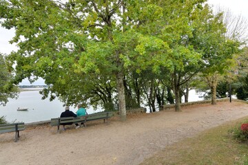 Two men sitting on a bench in front of the sea at Saint-Cado in Brittany France