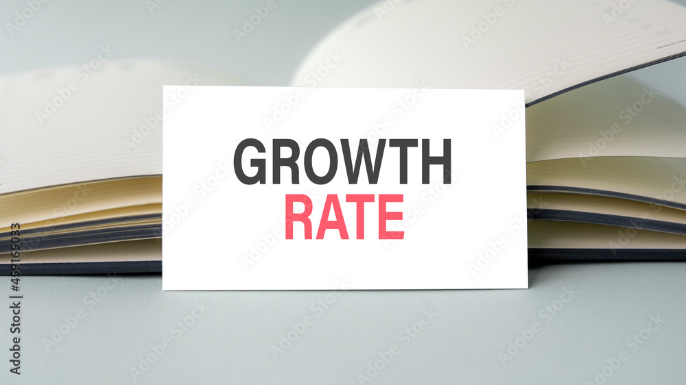 Poster a white business card with growth rate text stands on a desk against the background of an open diary