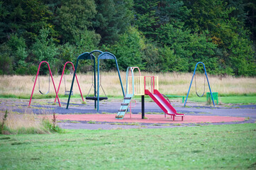 Empty playground derelict swings and slide in rural area