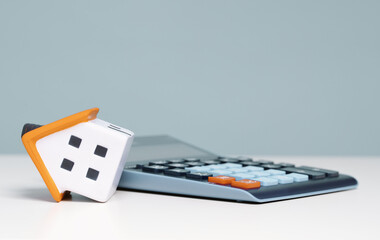 mortgage calculator or real estate business concept. Office desk with a bend over house and...