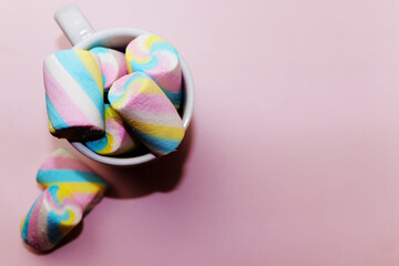 Colorful marshmallows candy in a white cup on a pink background