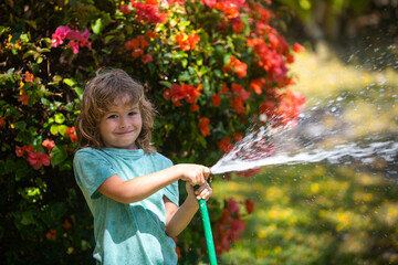 Funny little boy playing with garden hose in backyard. Child having fun with spray of water. Summer outdoors activity for kids.