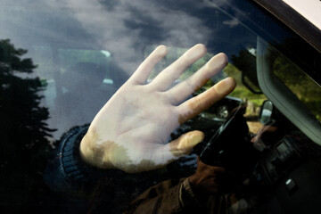 A hand of a child or young woman locked in the car with the reflections of forest trees....