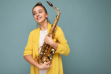 Shot of beautiful cute happy smiling brunette little female teenager wearing trendy yellow jacket...