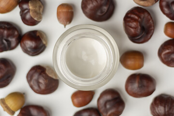 Concept of autumn skincare. Top down view of a jar of moisturizer and chestnuts. 
