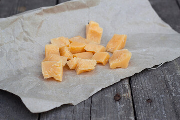 Parmesan cheese pieces on wooden table. 