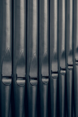 Dark metal organ pipes at an angle.