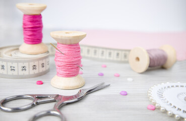 A spool of thread, scissors,a needle and buttons on a wooden table. Sewing accessories