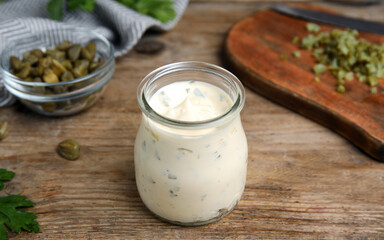 Tasty tartar sauce in glass jar on wooden table