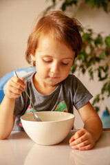 Obraz na płótnie Canvas Portrait of beautiful little child girl eats breakfast. Vertical image.