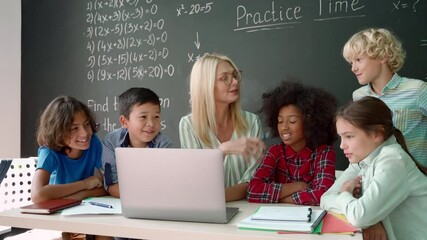 Happy diverse junior school children students gather at teacher table teaching kids looking at laptop computer using online software learning web education tech study together at class in classroom. - Powered by Adobe