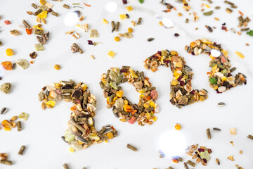 Number 2022 made of granola food isolated on white background with cereal grains around and blurred Christmas lights. Happy New Year or Christmas dieting concept.