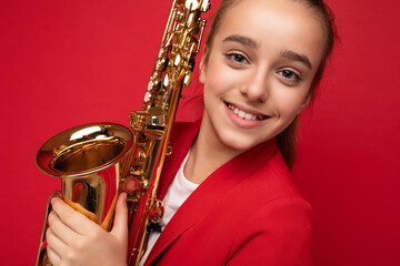 Closeup portrait photo shot of beautiful happy smiling brunette little girl wearing stylish red...