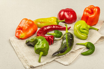 Trendy ugly organic multicolored peppers on stone concrete background