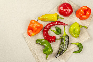 Trendy ugly organic multicolored peppers on stone concrete background