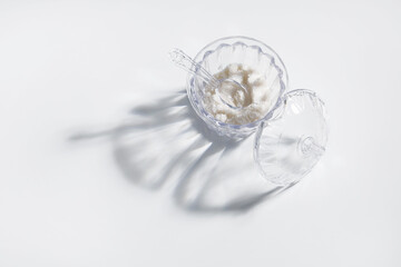 Salt or sugar in transparent jar with shadow on white background