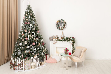 Christmas decorated tree in soft pink colors against the background of white classic fireplace with Christmas decorations. Details of New Year festive living room interior