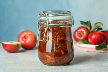Tasty apple jam in glass jar and fresh fruits on light table