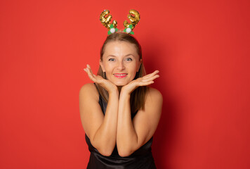Happy excited young woman in santa claus hat isolated over red background