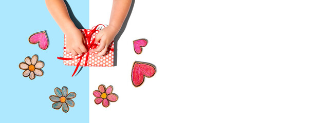 Little boy making a gift box with flowers and hearts drawings overhead view