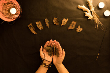 oráculo o lectura de runas de madera con manos de mujer sobre fondo negro  