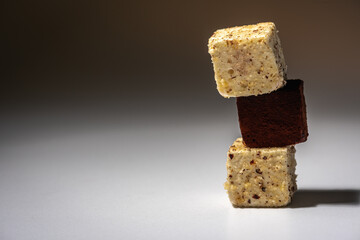 Pieces of white and chocolate chip cookies arranged on top of each other, like a pyramid, on a light background. Sweet concept