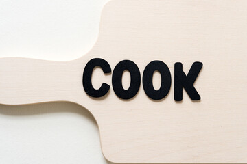 the word "cook" on a plain wooden paddle board