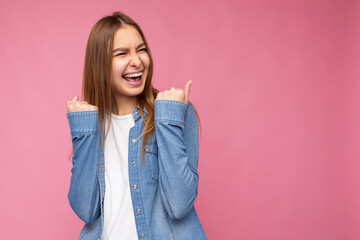 Photo of young positive happy smiling beautiful woman with sincere emotions wearing stylish clothes isolated over background with copy space and celebrating winning
