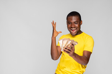 young nigerian man rejoicing while holding a lot of money he won