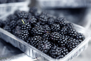 Ripe juicy blackberries in a plastic container.