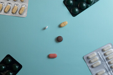 Multicolored pills and blister packs on blue background