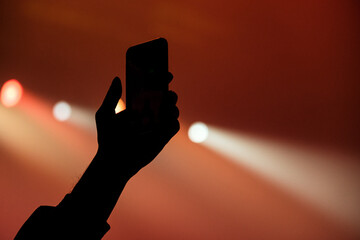 Silhouette of a hand with a smartphone at a concert