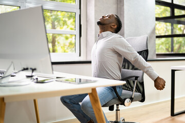 Employee Stretching At Office Desk