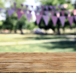 Empty wooden table in park decorated with bunting flags, space for design. Outdoor party