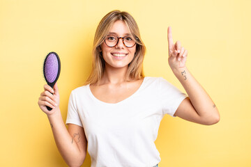 pretty blonde girl feeling like a happy and excited genius after realizing an idea. hair brush...