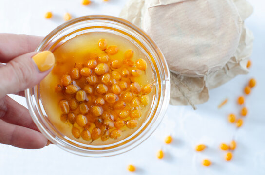 A woman holds in her hand homemade sea buckthorn jam useful for immunity in a bowl. Confiture is any fruit jam, marmalade, or stewed fruit in thick syrup