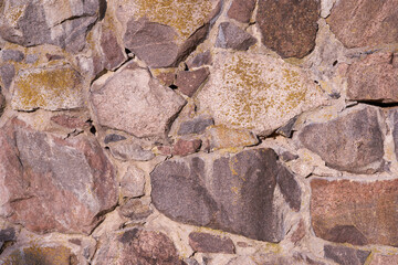An old wall of granite stones of different sizes as a background.