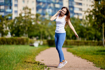 Smiling caucasian woman talks by smartphone outdoors.