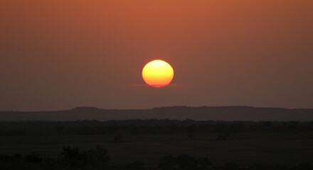 Gorgeous view of the sun during sunrise coming over small mountains in Texas. 