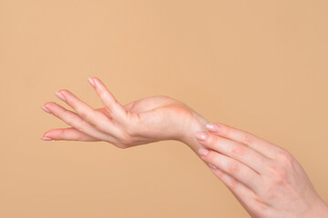 Hand care. Beautiful woman's hands on the beige background. Beautiful woman hands with cream.