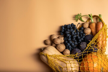 Autumn vegetables and fruits in shopping eco-friendly bag on ocher background, top view, copy...
