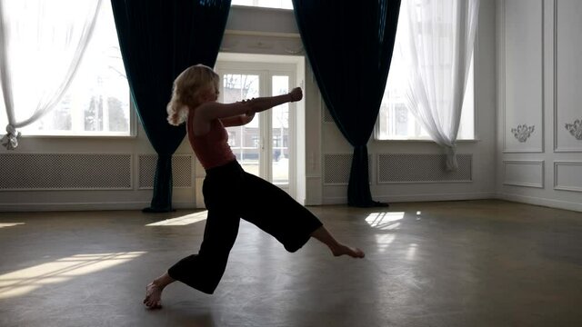 talented young woman is dancing alone in dance hall, practicing modern choreography