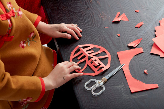 Cute Asian little girls are making decorations with traditional Chinese New Year atmosphere, indoors